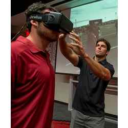 STriVR CEO Derek Belch adjusts the Rift virtual reality headset on Arkansas Razorbacks quarterback Brandon Allen.