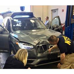 U.S. National Transportation Safety Board investigators examine a self-driving Uber vehicle involved in a fatal accident in Tempe, AZ, in March.