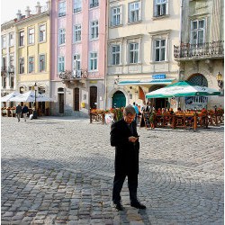 man on cobblestone street examines mobile phone