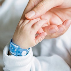 adult hand holds baby's hand