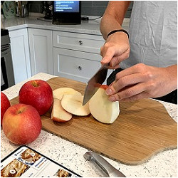 man slicing fruit on kitchen cutting board