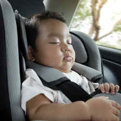 An infant asleep in a car seat.