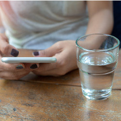 glass of water and woman's hands holding a smartphone