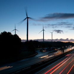 wind turbines by a road at dusk