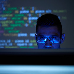 programmer in dark room with code projection