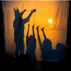 shadows on a curtain of a performer and reaching children