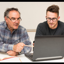 older man and a younger man looking at a laptop computer