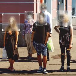 group of people standing outside, with faces shielded and obscured