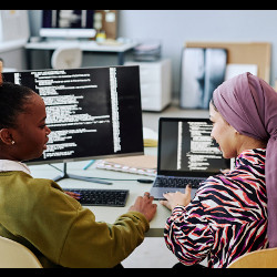 two women in discussion in front of computer displays