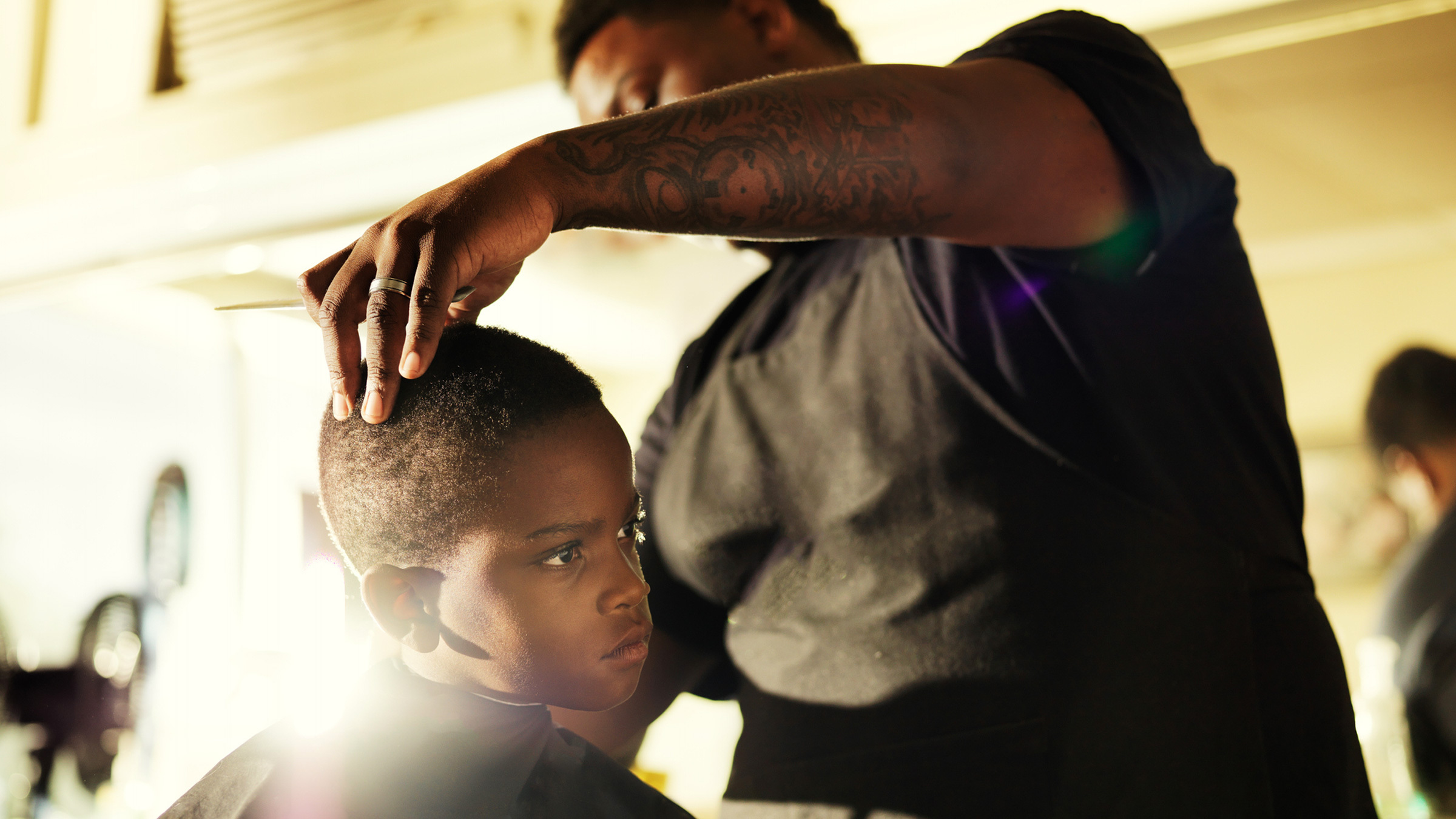 black barber giving a haircut to a black boy