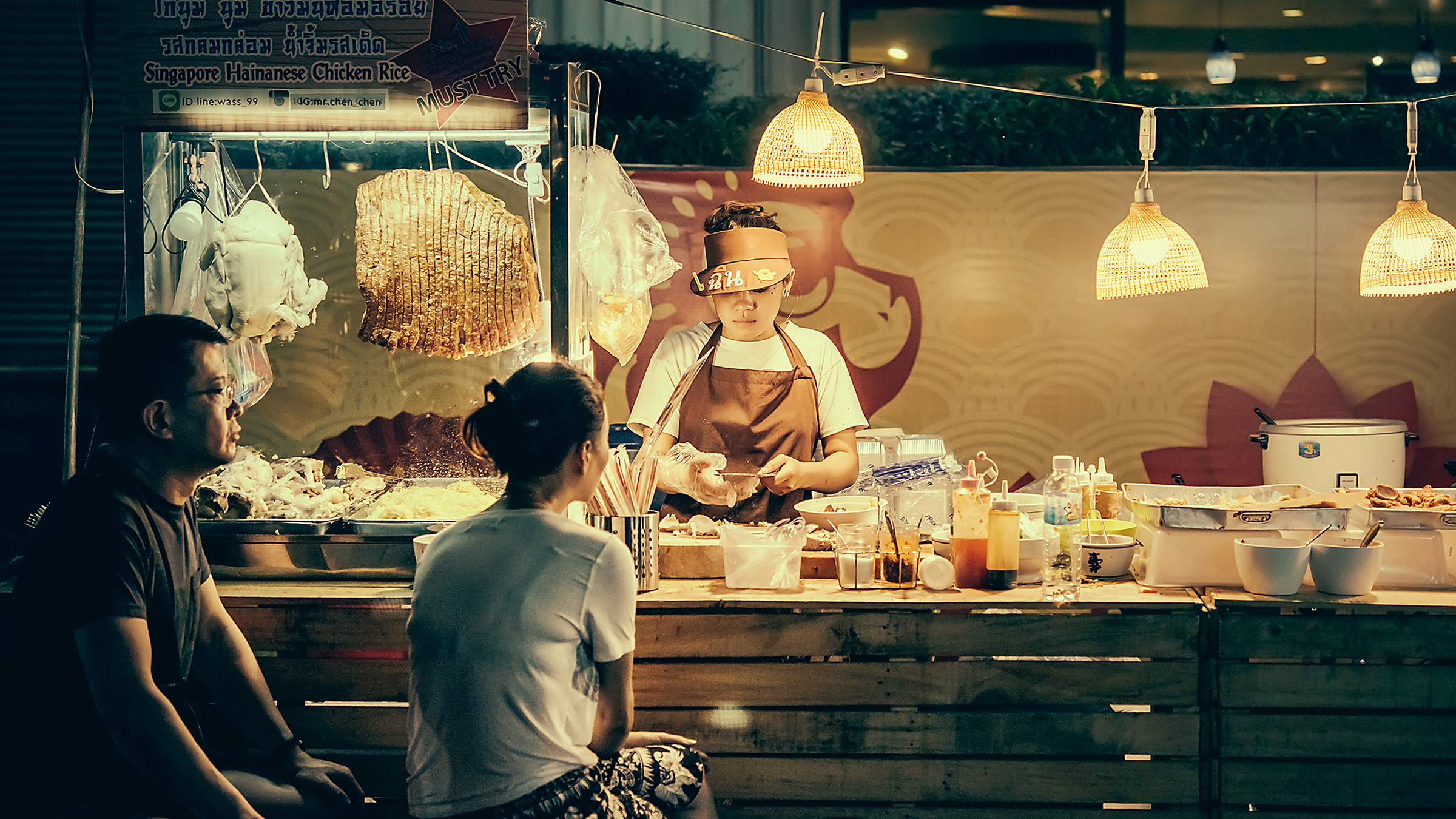 two customers sitting at an Asian food stand