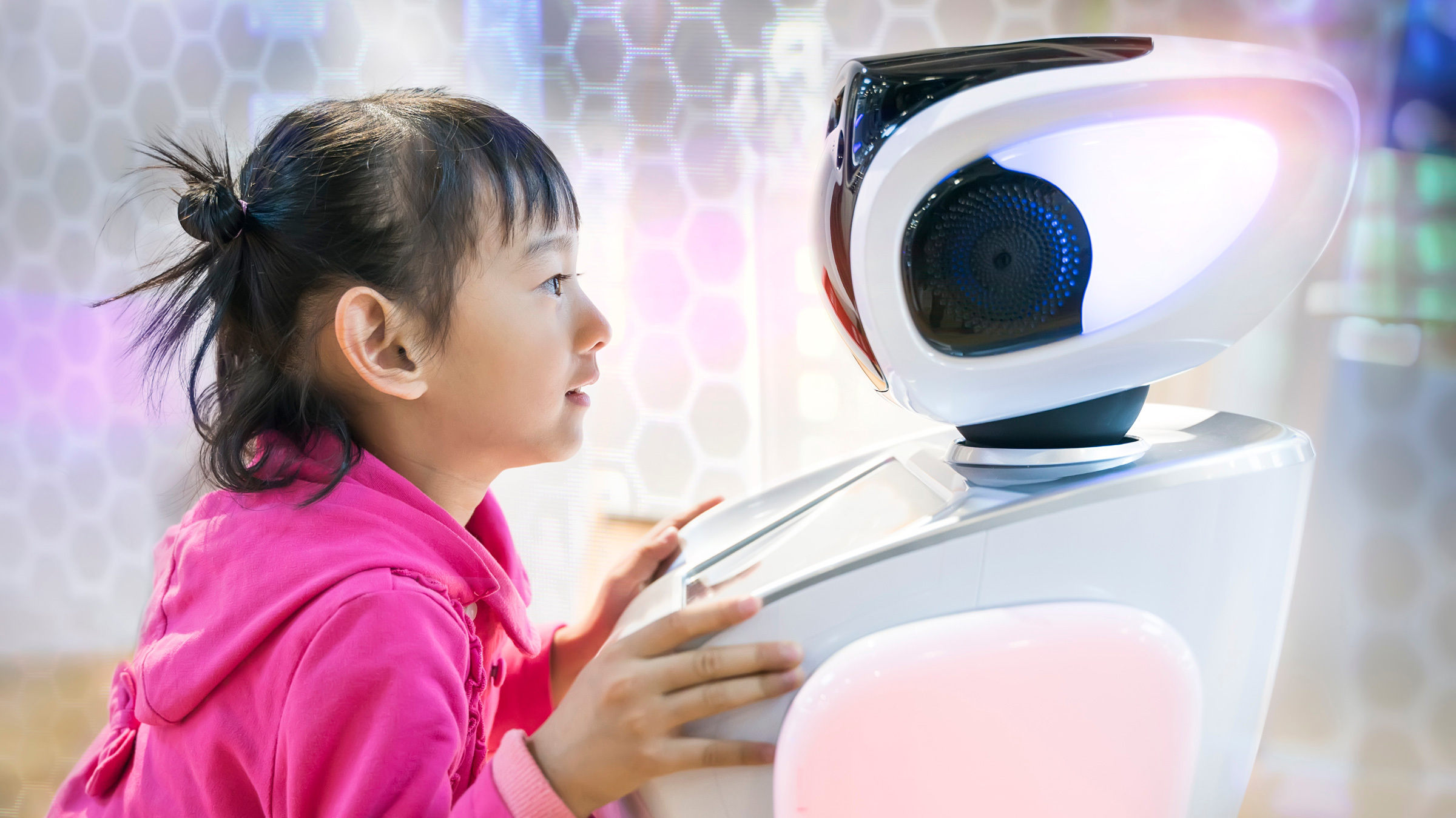 a young girl looks at and leans into the face of a humanoid robot