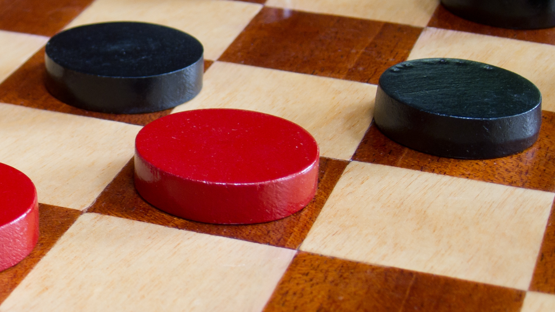 a few red and black pieces on a checker board