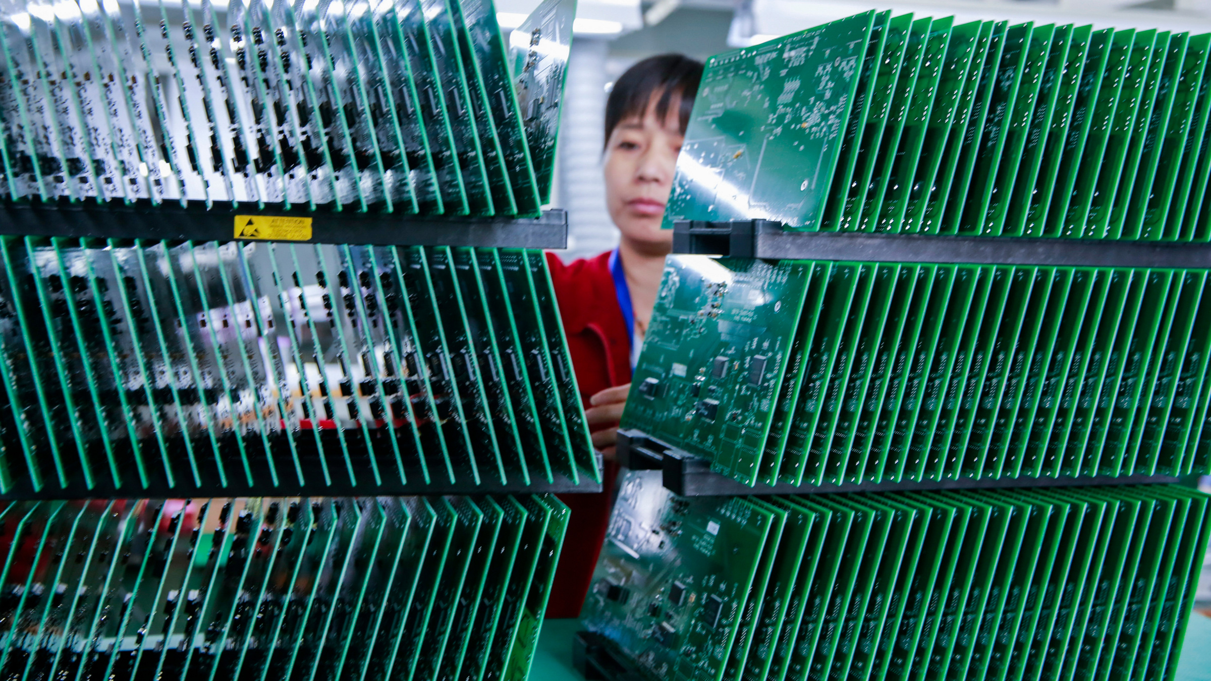 worker amidst rows of circuit boards at Chinese factory